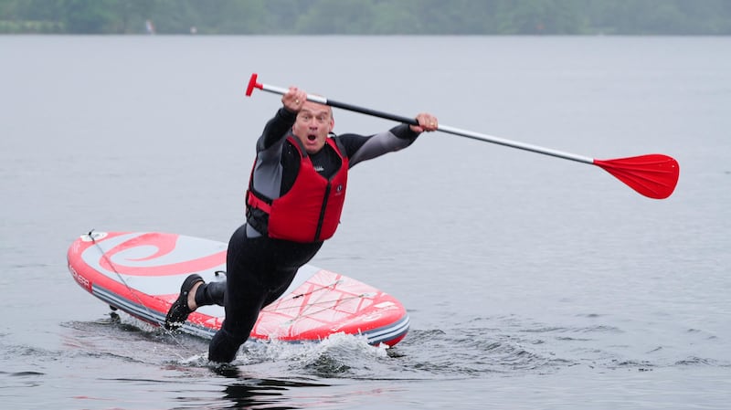 Ed Davey falls into the water while paddle boarding on Lake Windermere. PA