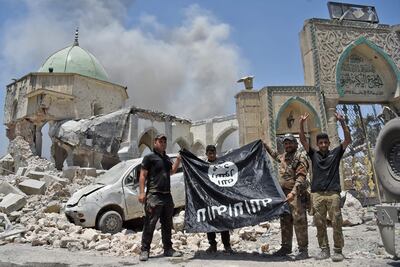 (FILES) In this file photo taken on June 30, 2017, members of the Iraqi Counter-Terrorism Service (CTS) with a flag of the Islamic State held upside-down, outside the destroyed Al-Nuri Mosque in the Old City of Mosul, after the area was retaken from IS. Even as the last pockets of resistance in eastern Syria hold their ground, the Islamic State group is shapeshifting into a new, but no less dangerous, underground form, experts warn. Also known as ISIS, or the Islamic State in Iraq and Syria, it had long been ready to cede the territory it once held in its self-styled "caliphate," and has already begun the switch to a more clandestine role, closer to its roots.  / AFP / FADEL SENNA / TO GO WITH AFP STORY by Michel MOUTOT, "Islamic State not defeated, just transforming, experts say"
