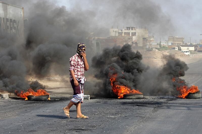 A Yemeni man walks by burning tyres as protesters demonstrate against inflation and the rise of living costs in the country's second city of Aden, which is held by forces loyal to the Saudi-backed government.  AFP