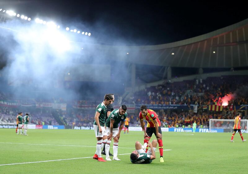 Al Ain, United Arab Emirates - December 18, 2018: A player goes down injured as flares go off during the game between Espérance de Tunis and Guadalajara in the Fifa Club World Cup. Tuesday the 18th of December 2018 at the Hazza Bin Zayed Stadium, Al Ain. Chris Whiteoak / The National