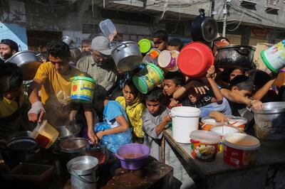 Palestinians crowd together as they wait for food in Rafah. AP 