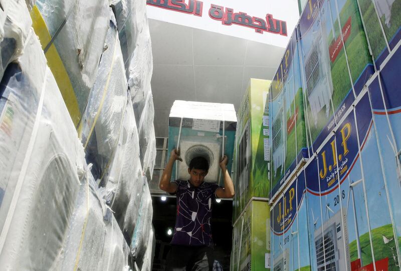 A labourer carries a washing machine at a store in Baghdad, Iraq. Sabah Arar / AFP
