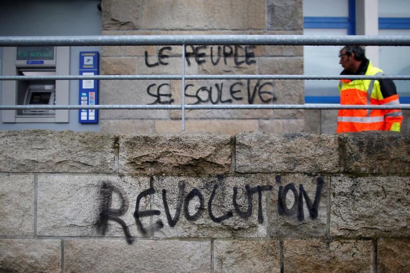 A man looks at the slogan which reads 'Revolution - The people are rising up' written on a wall in Dinard, France. Reuters
