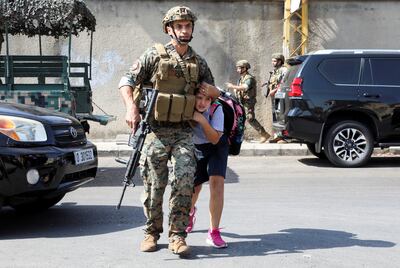 An Lebanese Army soldier shields a child crossing the road in Beirut. Reuters