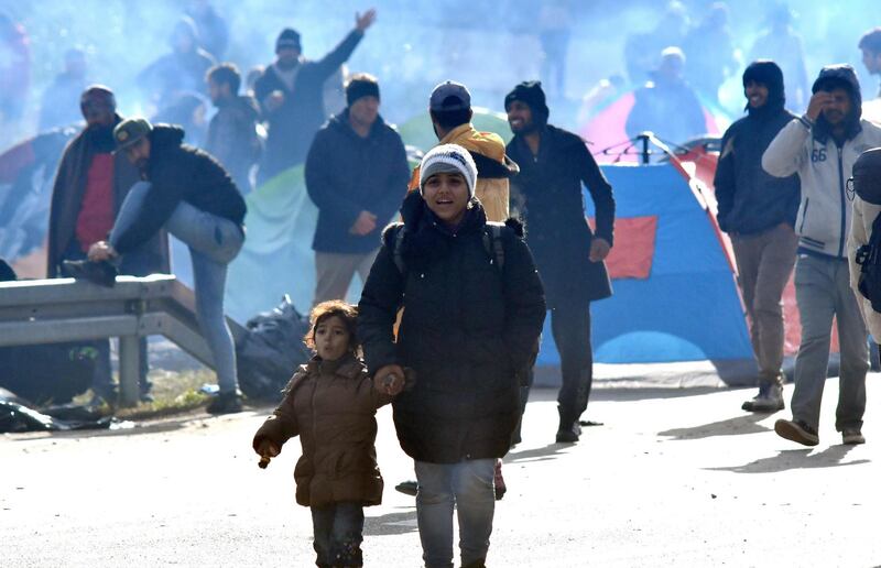 An Asian migrant woman with child, walks down the road, in the vicinity of Maljevac border crossing near Northern-Bosnian town of Velika Kladusa, on October 24, 2018. Illegal migrants gathered near the border crossing in an attempt to cross into neighboring Croatia. Officers of Bosnian border police and Croatian police prevented the migrans from crossing the border line between the two countries. Numbers of migrants who are passing through Bosnia during the past few months on their way towards the European Union, is on a constant raise. Migrants stop in Sarajevo where they rest before continuing their journey towards North-Western Bosnia and Croatian border. Until recently, Bosnia and its mountainous terrain were avoided by migrants travelling from northern Africa, Middle East or Asia, who, despite the closure of EU borders in March 2016, continued to pass through the Balkans. But, since late 2017 Bosnia is facing the passage of thousands of migrants, who are now stranded.  / AFP / MILAN RADULOVIC
