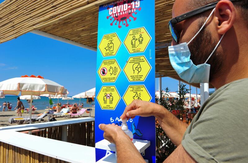 A man wearing a protective face mask sanitizes his hands on a beach that was reopened last week after months of closure due to an outbreak of the coronavirus disease (COVID-19), in Castiglione della Pescaia, Italy May 31, 2020. REUTERS/Jennifer Lorenzini
