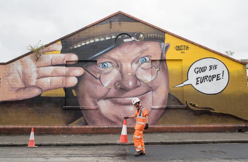 A construction worker moves a traffic cone in front of artwork by Odeith  in Bristol, England. Matt Cardy / Getty Images