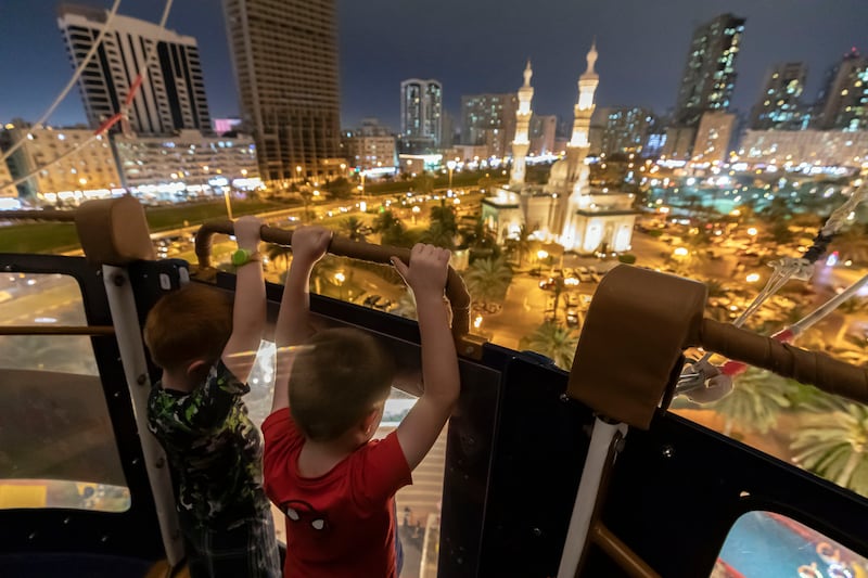 Children go up in the balloon with the Sharjah skyline in front of them 