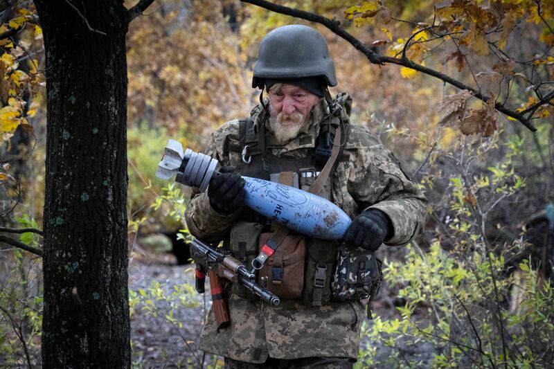 A Ukrainian soldier carries a shell near Bakhmut in the Donetsk region, Ukraine. AP