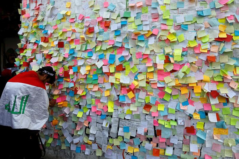 An Iraqi demonstrator pastes a note with his wish at a wall of wishes, during ongoing anti-government protests, at the building called 'the Turkish Restaurant Building', in Baghdad. REUTERS