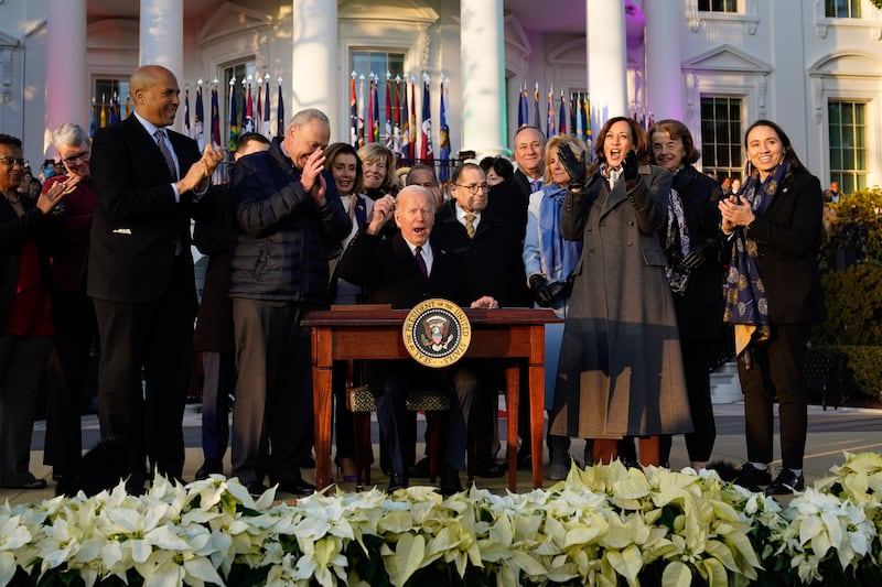 Mr Biden raises his pen after signing the bill. AP