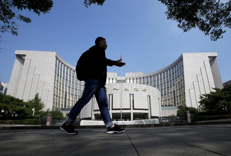 FILE PHOTO: A man walks past the headquarters of the People's Bank of China (PBOC), the central bank, in Beijing, China September 28, 2018. REUTERS/Jason Lee/File Photo