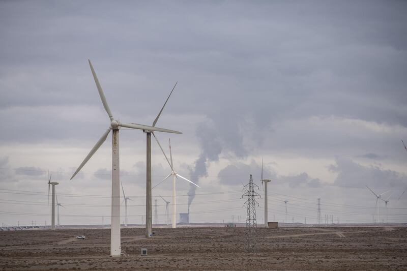 Wind turbines in front of a coal-fired power plant on the outskirts of the new city area of Yumen, Gansu province, China, on Wednesday, March 31, 2021. Yumen, "the cradle of China's oil industry," has become a totem for China's changes over the past four decades—from a time of sacrifice and ideology to one of entrepreneurs and the pursuit of wealth, from the old economy to the new, from fossil fuels to renewable energy. Photographer: Qilai Shen/Bloomberg