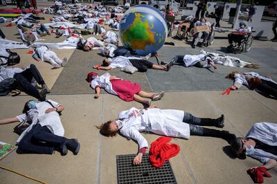 Doctors for Extinction Rebellion lay down prior to march to the WHO headquarters during a protest on the sideline of the WHO's World Health Assembly in Geneva on May 29, 2021. Hundreds of health workers marched to the WHO demanding that authorities in all countries recognise and act to counter the health risks of climate change. / AFP / Fabrice COFFRINI
