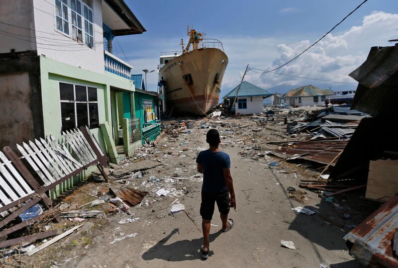 A man walks past a ferry boat that was swept ashore near Palu when a magnitude 7.5 quake and tsunami hit Indonesia's Central Sulawesi province September 28, 2018. Dita Alangkara / AP Photo