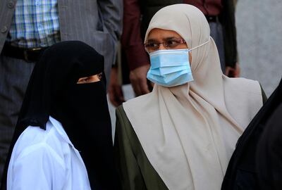 A Yemeni woman wearing a protective mask stands next to a fully-veiled fellow Yemeni outside a hospital in Sanaa, as Yemen's coronavirus committee urged the government on March 24, 2021 to declare a public health "state of emergency" after a surge in  COVID-19 infections in the war-torn country. Six years of civil war has left Yemen's weak healthcare system in ruins, and this week the country reported more than 100 cases in a day, much higher than figures at the beginning of the year. / AFP / MOHAMMED HUWAIS
