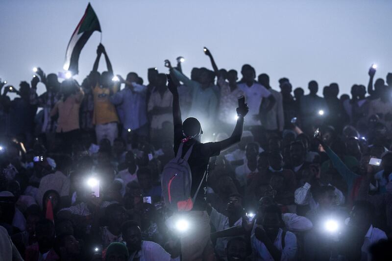 Sudanese protesters open their smartphones lights as they gather for a "million-strong" march outside the army headquarters in the capital Khartoum on April 25, 2019. Tens of thousands of protesters converged from all directions on Sudan's army headquarters after calls for a "million-strong" demonstration to demand the ruling military council cede power. / AFP / OZAN KOSE
