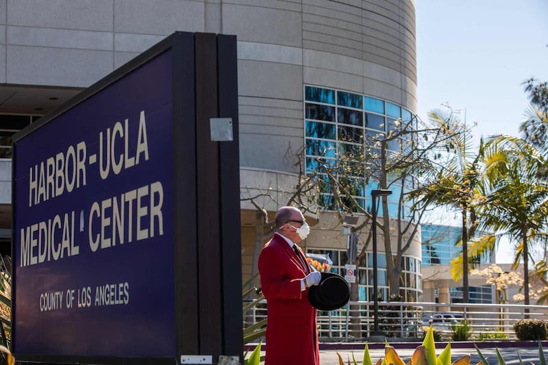 A fan holding flowers stands in front of the main entrance of the Harbor UCLA Medical Centre in Torrance, California on February 23, 2021, where the US Golf star Tiger Woods is hospitalised. AFP