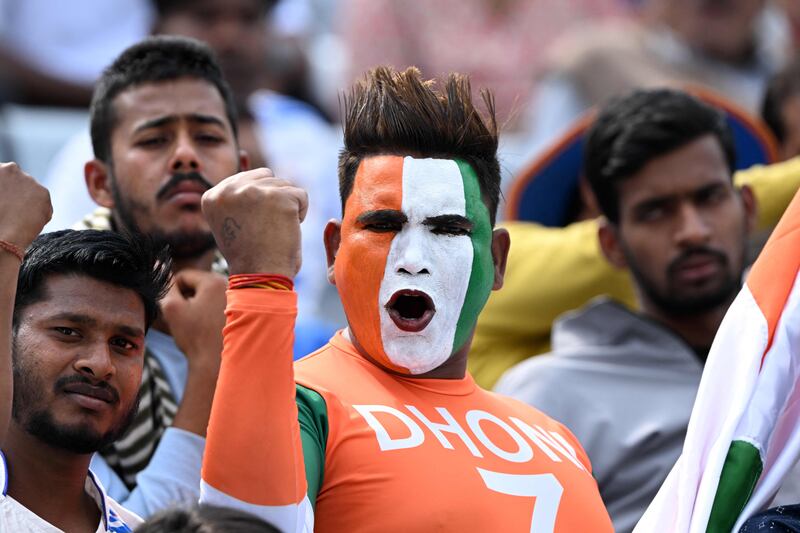 An Indian cricket fan with his face painted in the colours of the flag of India cheers from the stands. AFP