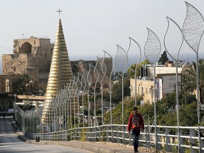 A man walks past a Christmas tree in Byblos, north of Beirut December 13, 2014. The Christmas tree, measuring about 30 metres (98 ft.) and made up of gold-coloured iron leaves, stands at the entrance of the ancient city of Byblos. REUTERS/Jamal Saidi (LEBANON - Tags: SOCIETY RELIGION) - GM1EACD1NIR01