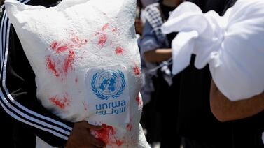 A Palestinian holds a representation of a United Nations Relief and Works Agency (UNRWA) aid sack with fake blood on it during a protest to mark the 76th anniversary of the Nakba, the "catastrophe" of their mass dispossession in the 1948 war surrounding Israel's creation, in Ramallah, in the Israeli-occupied West Bank, May 15, 2024.  REUTERS / Mohamad Torokman