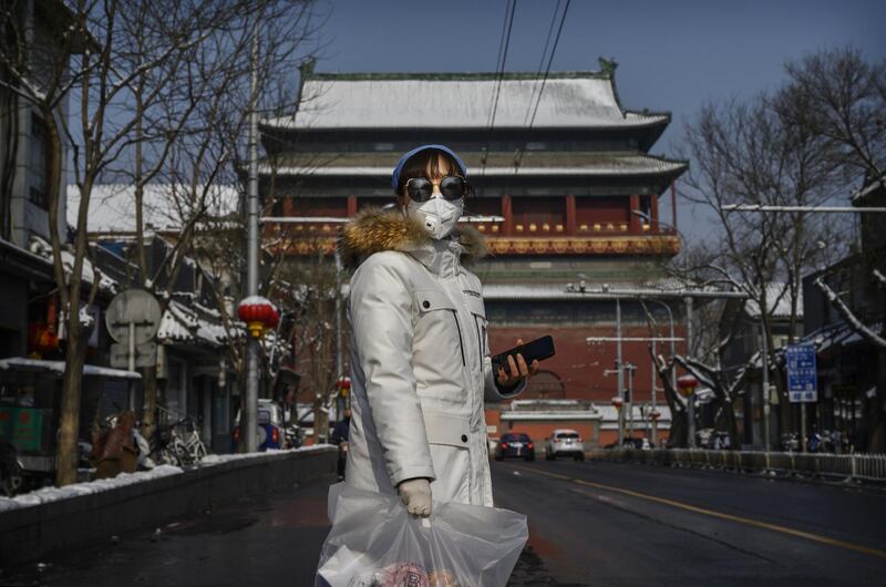 A Chinese woman wears a protective mask and rubber gloves as she walks by the Drum Tower in Beijing, China. Getty Images