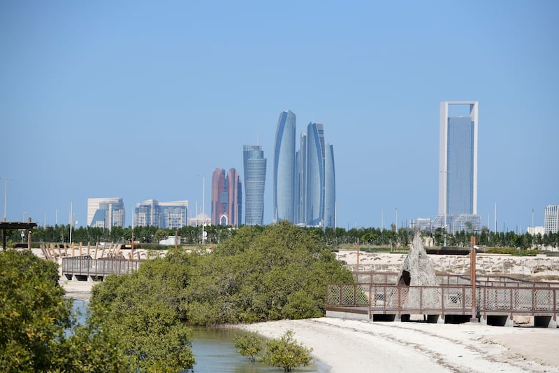 Adnoc's headquarters, right, in Abu Dhabi. The oil company has signed agreements with 23 businesses to boost the UAE's manufacturing sector. Khushnum Bhandari / The National