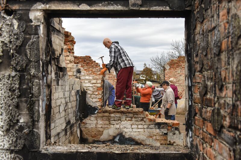 Volunteers clean the debris of a house destroyed by combat in Novoselivka village, Chernihiv region of Ukraine. Their work focuses on repairing roofs before the worst of the winter weather sets in. EPA 