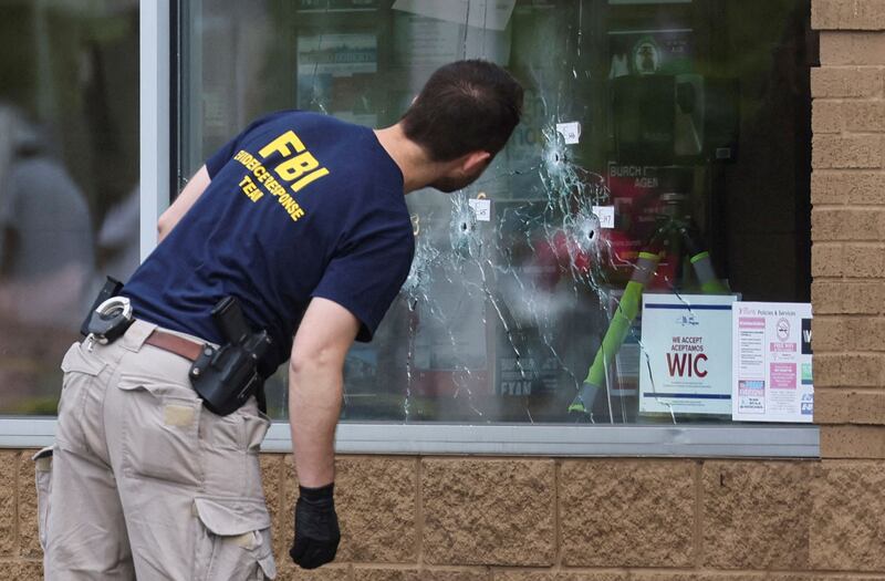 A member of the FBI looks at bullet holes through the glass at the scene of a shooting at a TOPS supermarket in Buffalo, New York. Reuters