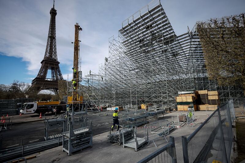 Workers build stands for this summer's Olympic Games on the Champ-de-Mars, beside the Eiffel Tower in Paris. AP
