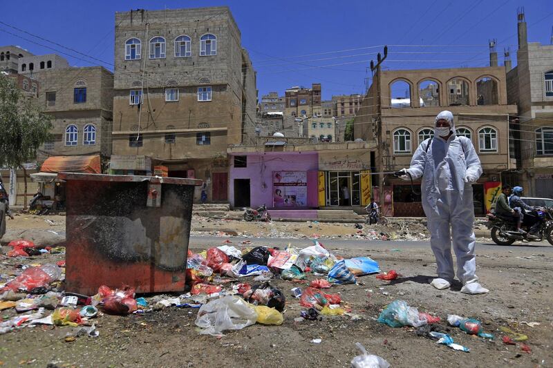 A Yemeni volunteer sprays disinfectant over garbage in the one of Sanaa's impoverished neighbourhoods, amid concerns of a coronavirus outbreak.   AFP