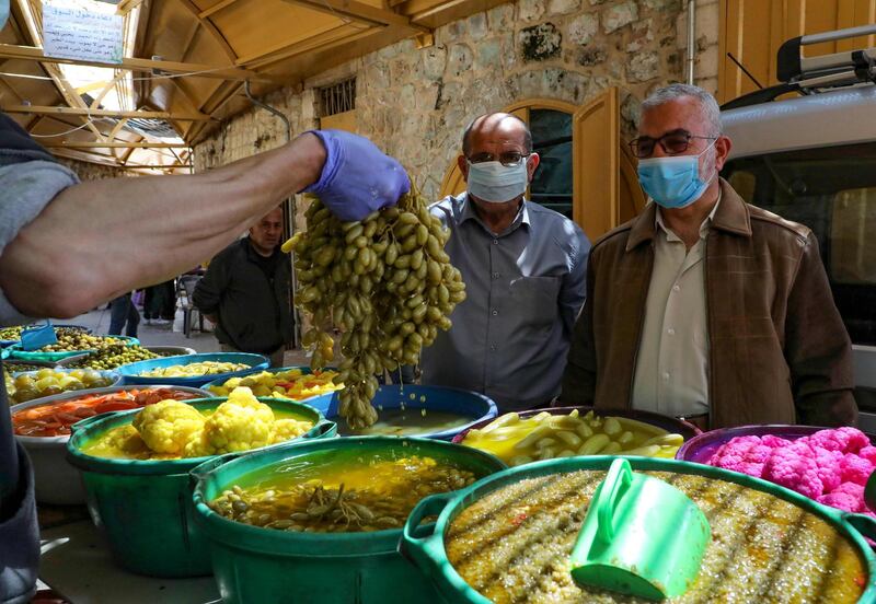 A Palestinian vendor shows pickled grapes to customers in the occupied West Bank city of Hebron.  AFP