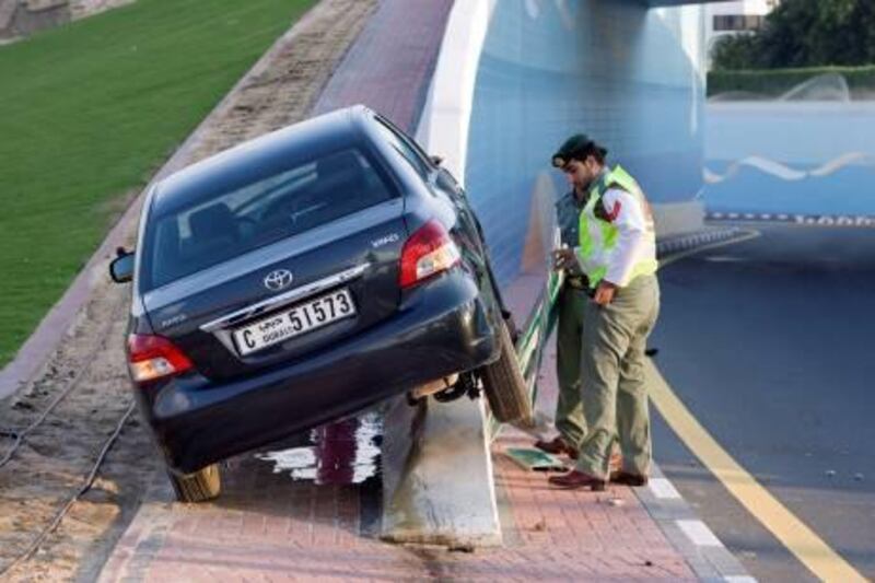 Dubai - December 26, 2009 - Police set an exit sign upright after the driver of this car missed a turn on Airport Road and drove up this flyover embankment in Dubai, December 26, 2009. The driver was not injured. (Photo by Jeff Topping/The National)
  *** Local Caption ***  JT004-1226-CAR STUCK ACCIDENT_MG_9062.jpg