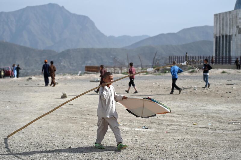 A boy carries a stick on his shoulder during a kite battle.