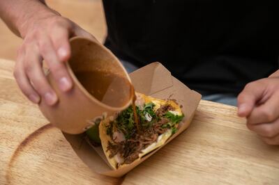 Pouring sauce on to a birria taco. Antonie Robertson / The National