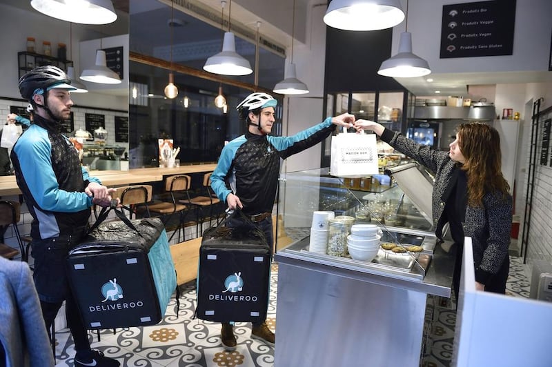 Bikers working for food delivery service Deliveroo enter a restaurant to pick up meals they will deliver. AFP