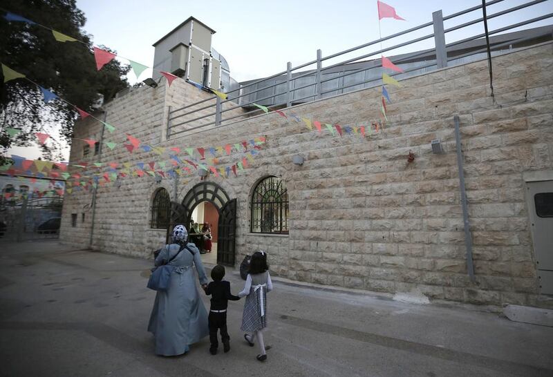 A mother and her children walk outside the Palestinian national theatre, known as Al Hakawati theatre, in east Jerusalem, on October 28, 2014. Ahmad Gharabli/AFP Photo