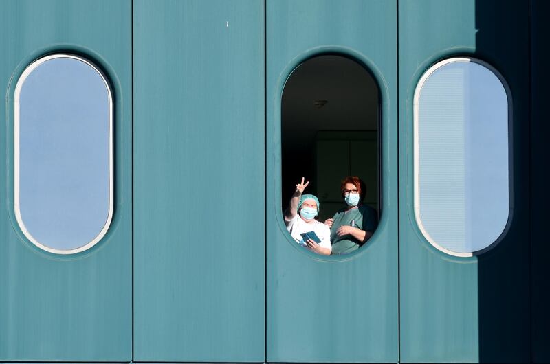 Medical staff show victory sign to the media at the window of the Dubrava hospital, Croatia. AFP