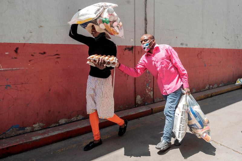 A woman walks with her blind husband as they carry a food parcel collected during a food distribution leaded by the international NGO Gift to the Givers, in Johannesburg CBD, on October 14. Luca Sola / AFP