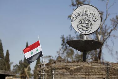 A Syrian national flag flutters next to ISIS's slogan at a roundabout where executions were carried out by ISIS militants in Palmyra. Omar Sanadiki