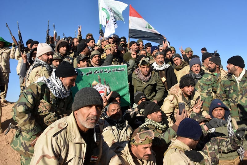 Members of the Imam Ali Division, one of the groups fighting within the Hashed al-Shaabi (Popular Mobilisation) paramilitaries, celebrate after the Iraqi Prime Minister declared victory in the war against the Islamic State (IS) group, about 80 kilometres (about 50 miles) along the Iraqi-Syrian border west of the border town of al-Qaim on December 9, 2017. / AFP PHOTO / STRINGER