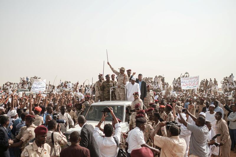 Mohamed Hamdan Dagalo (C), known as Himediti, deputy head of Sudan's ruling Transitional Military Council (TMC) and commander of the Rapid Support Forces (RSF) paramilitaries, waves a baton to supporters on a vehicle as he arrives for a rally in the village of Abraq, about 60 kilometers northwest of Khartoum, on June 22, 2019. (Photo by Yasuyoshi CHIBA / AFP)