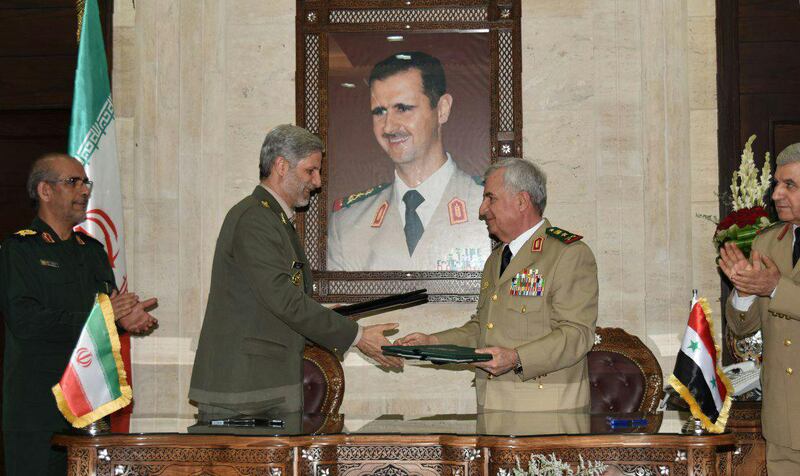 A picture relased by the official Syrian Arab News Agency (SANA) on August 26, 2018 shows Iranian Defence Minister Amir Hatami (L) meeting with his Syrian counterpart Abdullah Ayoub (R) in the capital Damascus. Behind them is a portrait of Syrian president Bashar al-Assad. - Iran's top defence official met Syria's President Bashar al-Assad and its defence minister on today in Damascus, hailing their strong ties and pledging to contribute to the war-torn country's reconstruction. (Photo by Handout / SANA / AFP) / == RESTRICTED TO EDITORIAL USE - MANDATORY CREDIT "AFP PHOTO / HO / SANA" - NO MARKETING NO ADVERTISING CAMPAIGNS - DISTRIBUTED AS A SERVICE TO CLIENTS ==