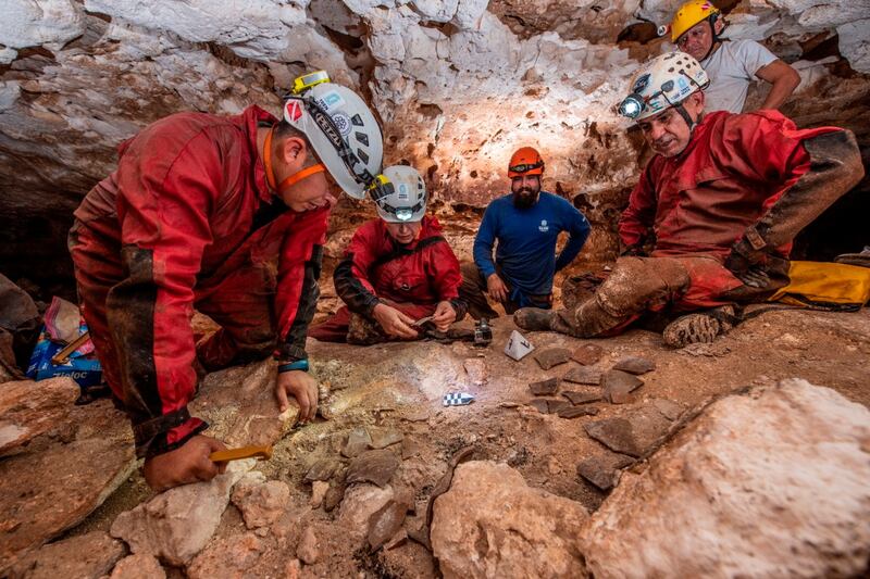 Archaeologists examine fragments of pottery in a cave during the construction of a tourist train, in the state of Yucatan.