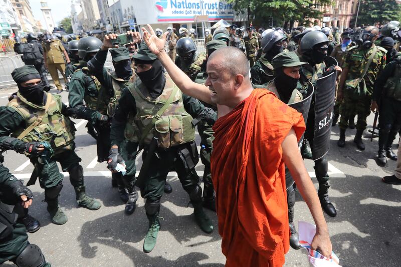 A protester walks in front of police during an anti-government protest, calling for the resignation of the president over his alleged failure to address Sri Lanka's economic crisis. EPA