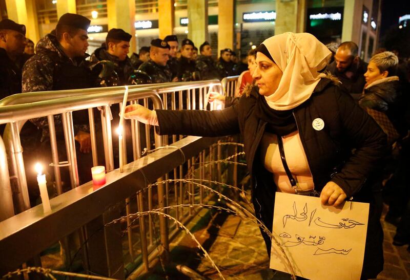 An anti-government protester holds an Arabic placard that reads: "You even stole the dream," as she lights a candle in front the riot police. AP