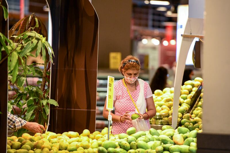 A shopper looks at fruit prices at a supermarket in Abu Dhabi. Nearly two thirds of consumers say they are cutting back. Khushnum Bhandari / The National