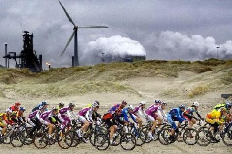 Cyclers, taking part in the 9th Egmond-Pier-Egmond ATB-Beach Race, pass in front of the Anglo-Dutch steel-factory Corus in the town of Wijk aan Zee.