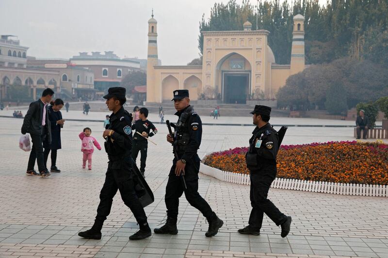 FILE - In this Nov. 4, 2017, file photo, Uighur security personnel patrol near the Id Kah Mosque in Kashgar in western China's Xinjiang region. China says on Monday, March 18, 2019 it has arrested nearly 13,000 people it describes as terrorists in the traditionally Islamic region of Xinjiang since 2014 and broken up hundreds of "terrorist gangs." The figures were included in a government report on the situation in the restive northwestern territory that seeks to respond to growing criticism over the internment of an estimated 1 million members of the Uighur and other predominantly Muslim ethnic groups. (AP Photo/Ng Han Guan, File)