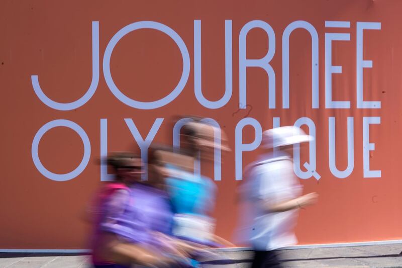 This picture taken shows people running in front of a sign reading "Journee Olympique" ("Olympic day") as they take part in the "Journee Olympique" ("Olympic day") in Paris. AFP